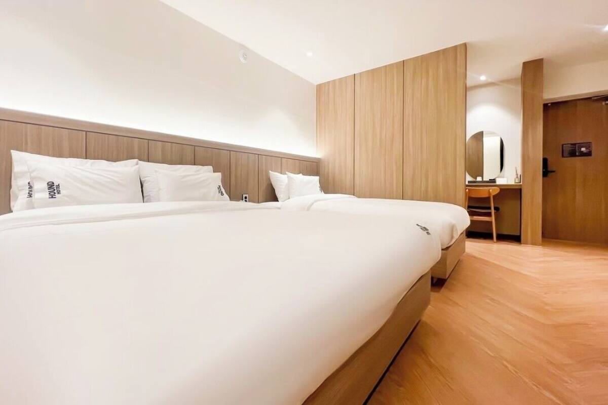 Una habitación de hotel moderna con una cama grande, cabecera de madera y un escritorio pequeño con una silla.