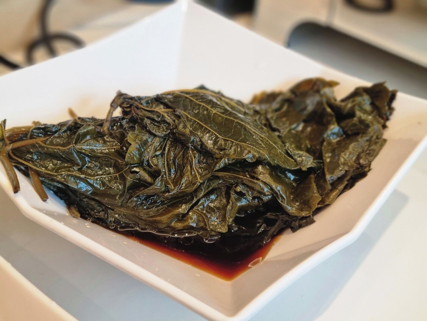 Un plato rectangular blanco con un líquido oscuro, posiblemente una salsa, en el fondo.