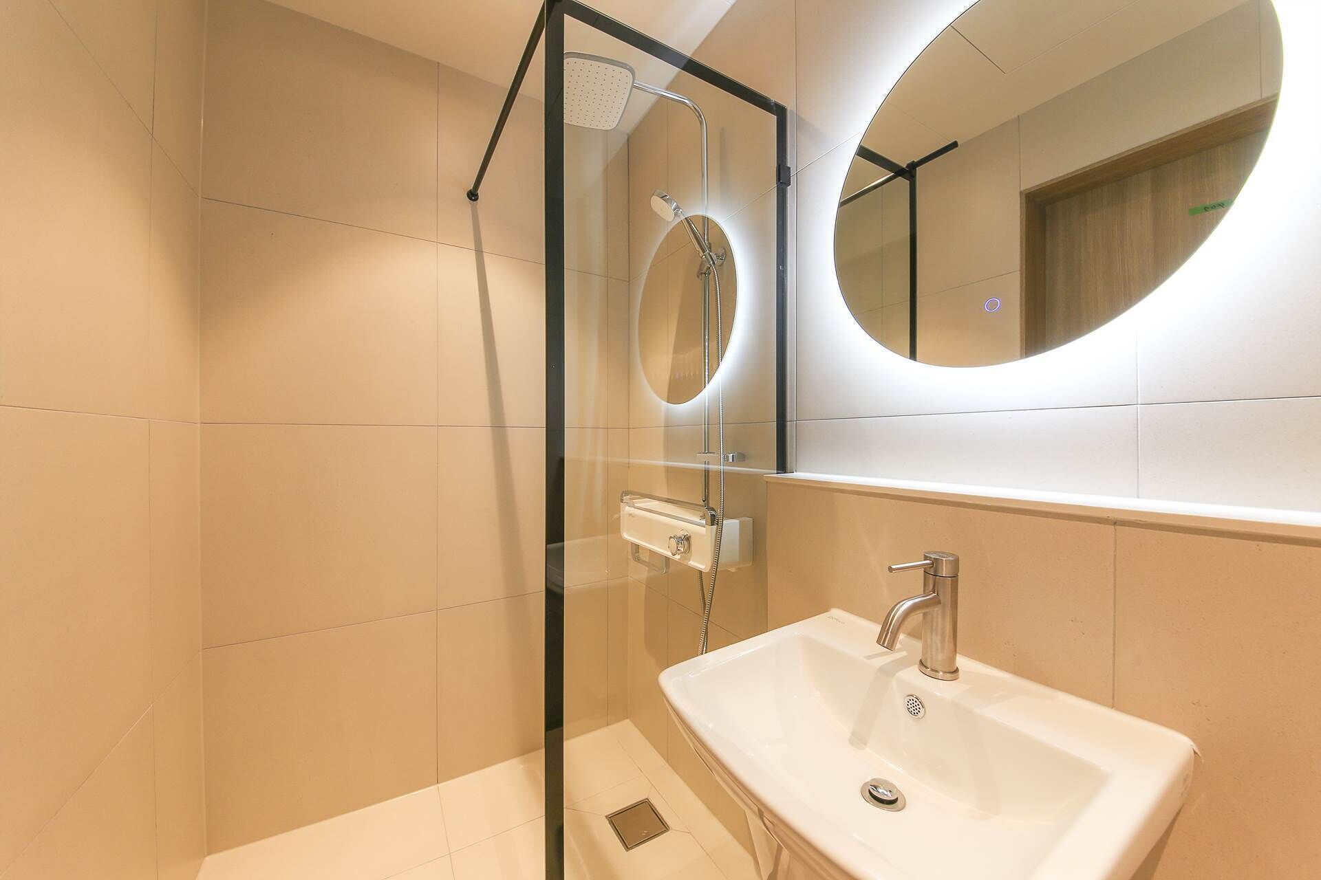 A modern bathroom with a glass-enclosed shower, a white sink, and a large mirror.