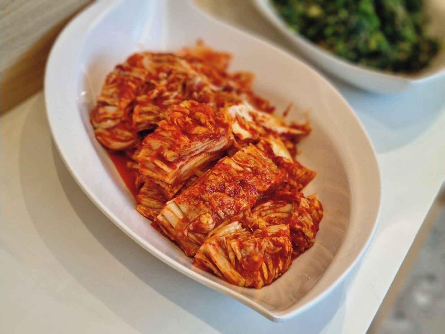 A white plate with kimchi on a table.