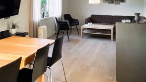 Un salon moderne avec une table à manger en bois, des chaises noires, un canapé et une table basse.