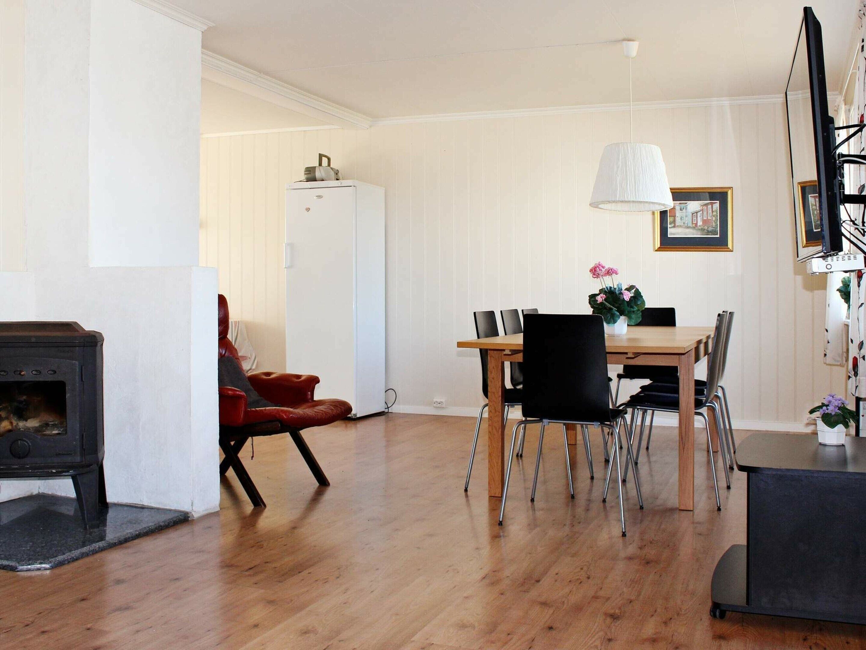 A dining area with a wooden table, black chairs, a white refrigerator, and a black stove.