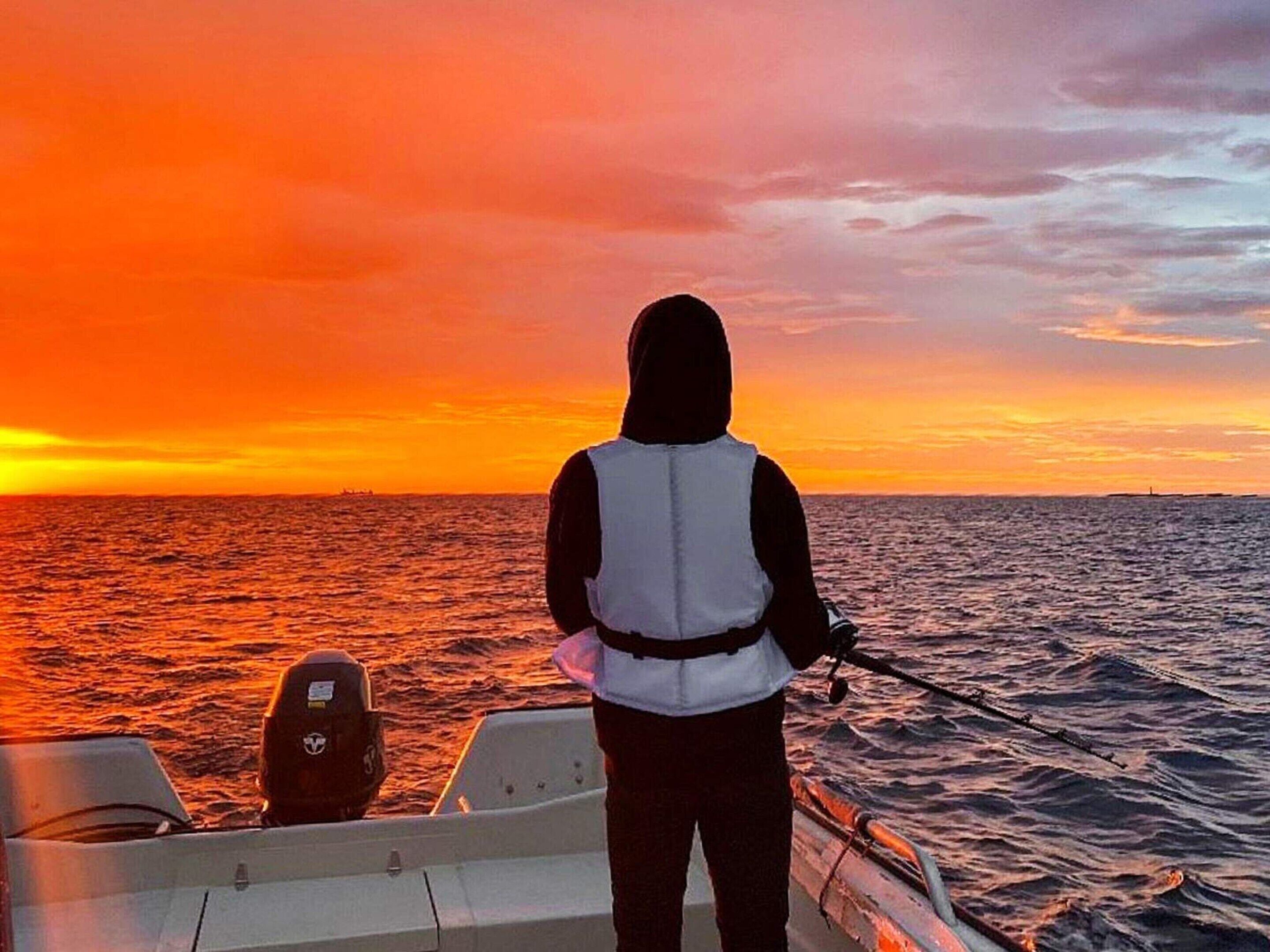 A person on a boat during sunset with a view of the ocean.