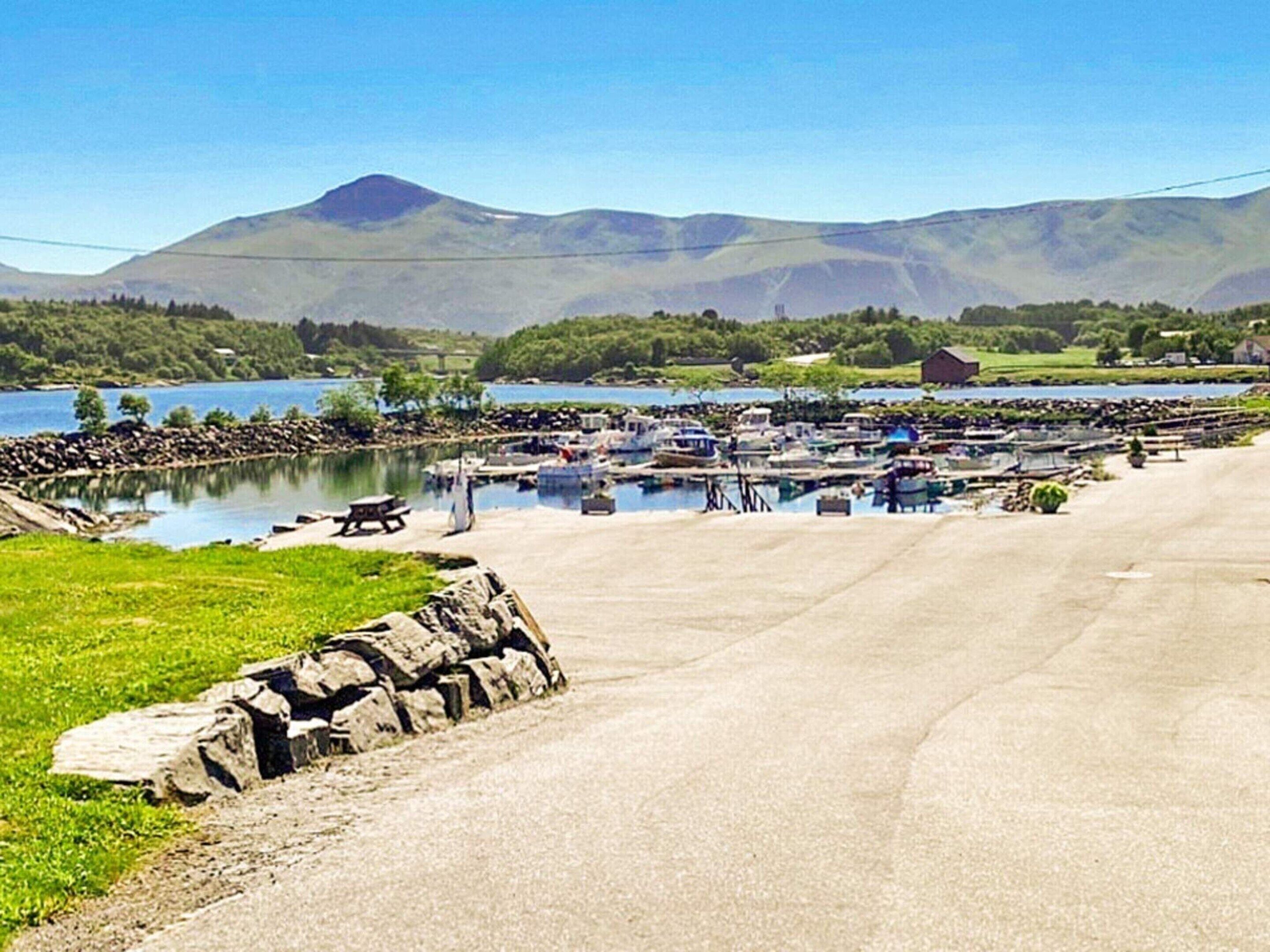 A marina with boats docked, a picnic table, and a stone wall.