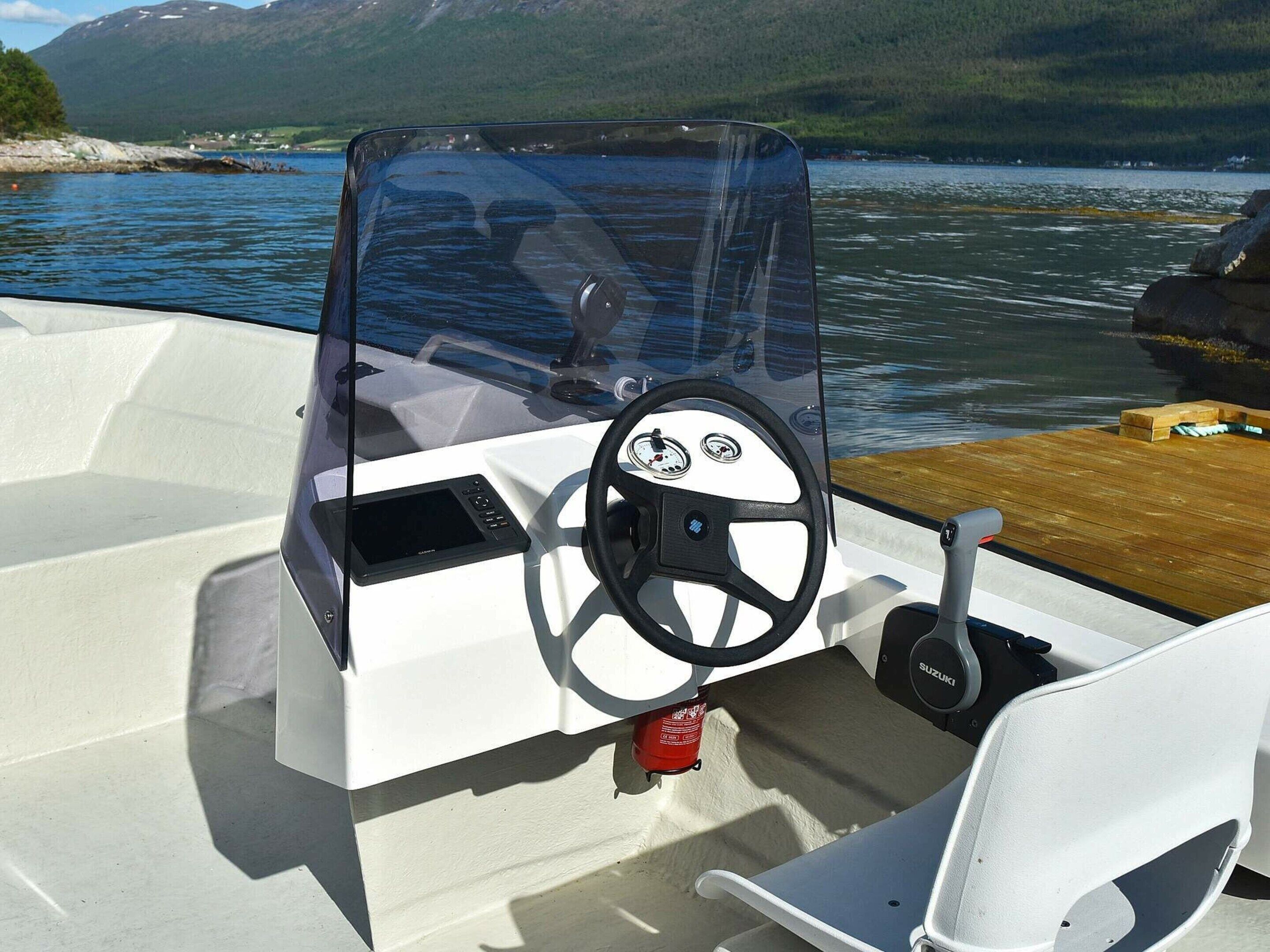 A boat's interior with a steering wheel, a Suzuki logo, and a control panel.