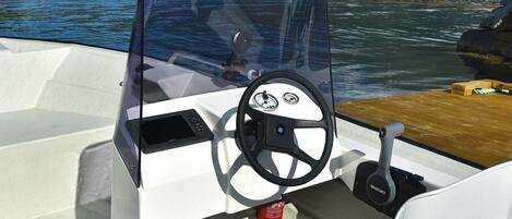 A boat's interior with a steering wheel, a Suzuki logo, and a control panel.