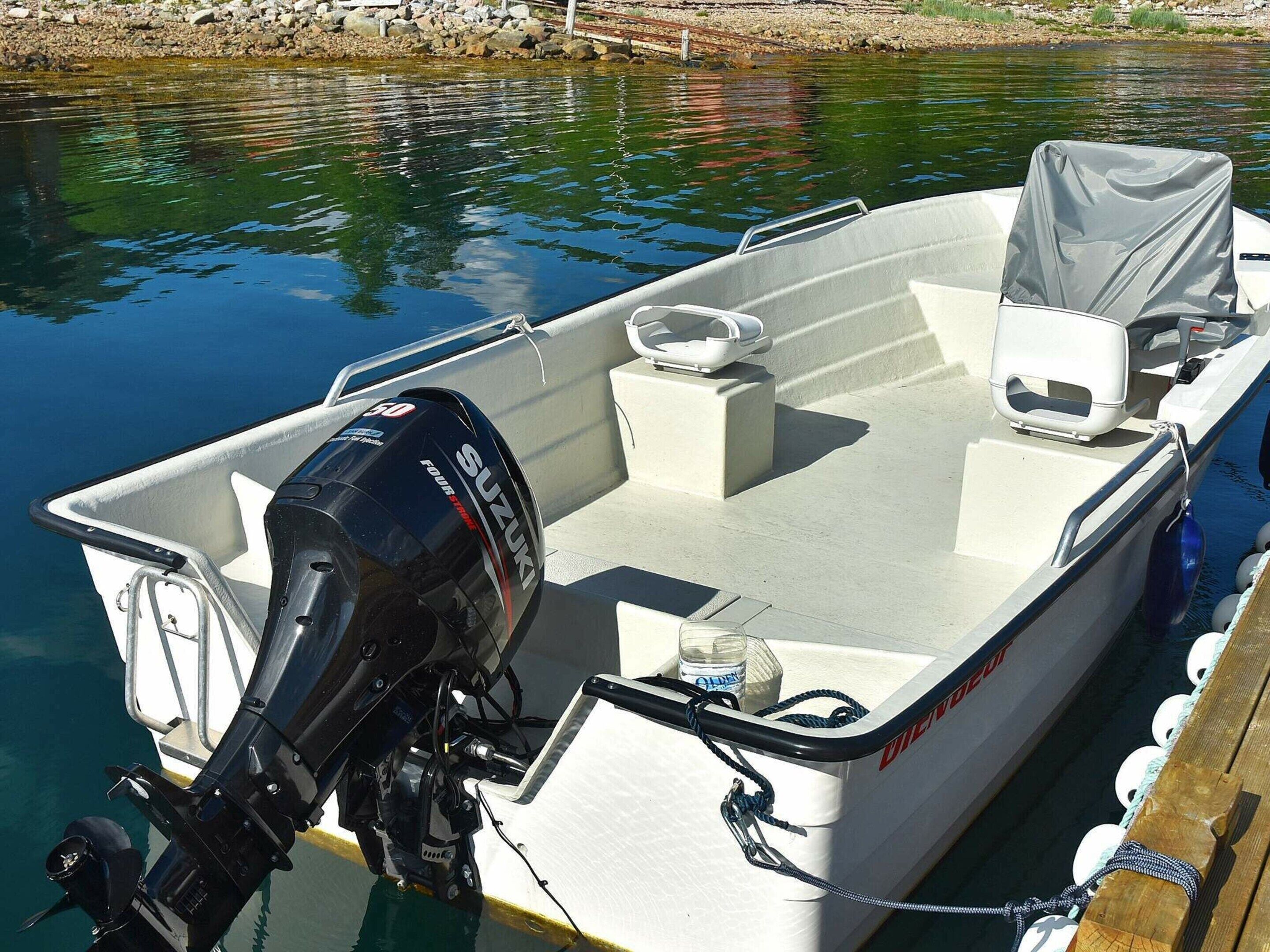 A boat with a Suzuki outboard motor, a white interior, and a covered area.