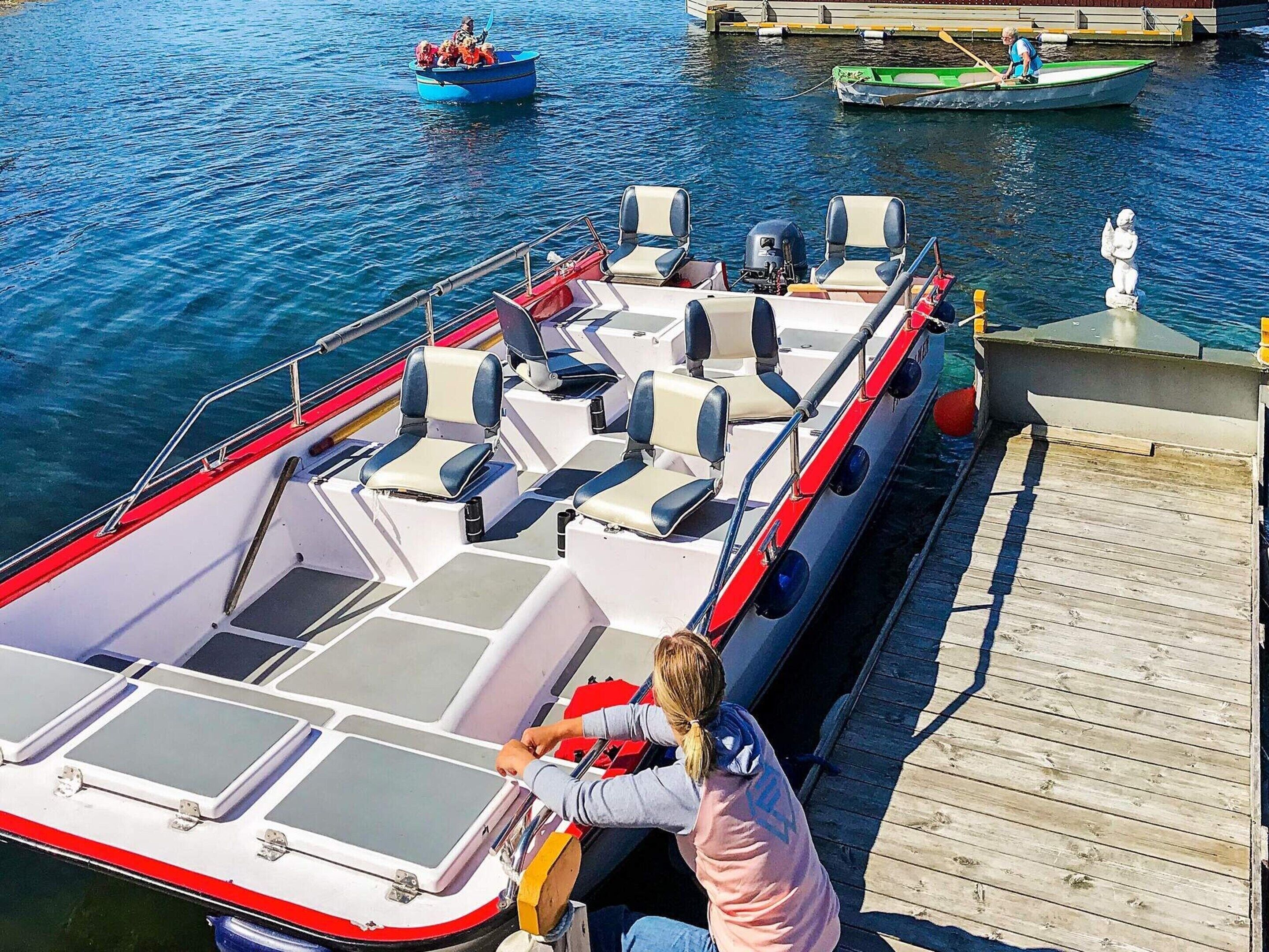 Un bateau était amarré à un quai, qui comportait plusieurs espaces aménagés pour s’asseoir, et une personne était aux commandes.