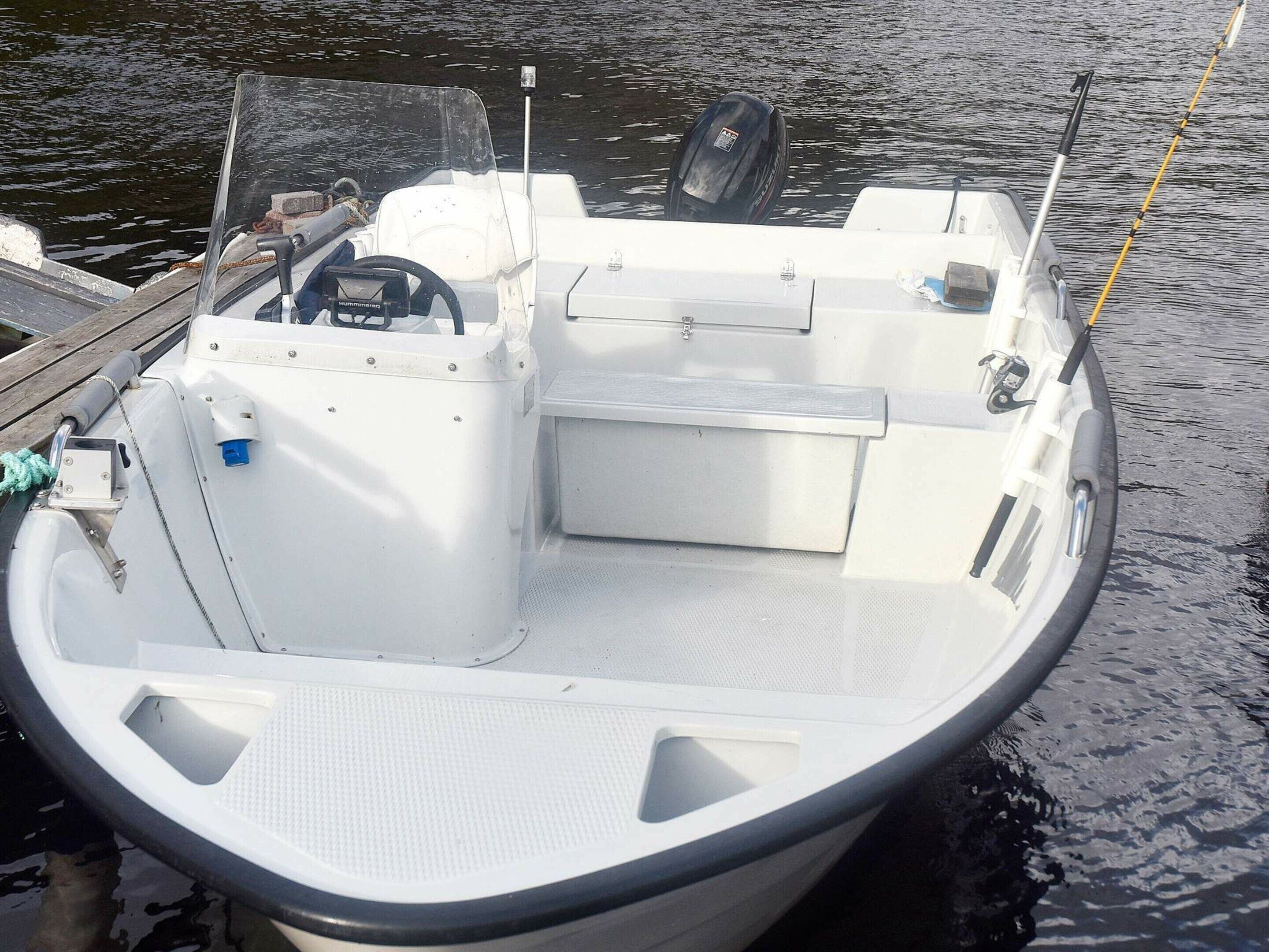 A small, white motorboat docked at a pier.