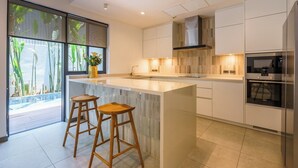 Una cocina moderna con una isla grande, electrodomésticos de acero inoxidable y vistas a una piscina.