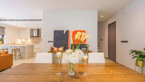 Una cocina moderna con armarios blancos, una isla de madera y una zona de comedor con mesa y sillas de madera.