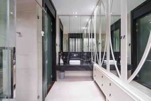 Un baño moderno con encimera de mármol negro, lavabo blanco y cabina de ducha con mampara de vidrio.