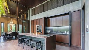A modern kitchen with a central island, bar stools, and a dining area with a chandelier. - The Oasis Tranquil Escape (Bangkok)