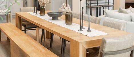 A wooden dining table with benches, a vase with dried flowers, and a bowl.