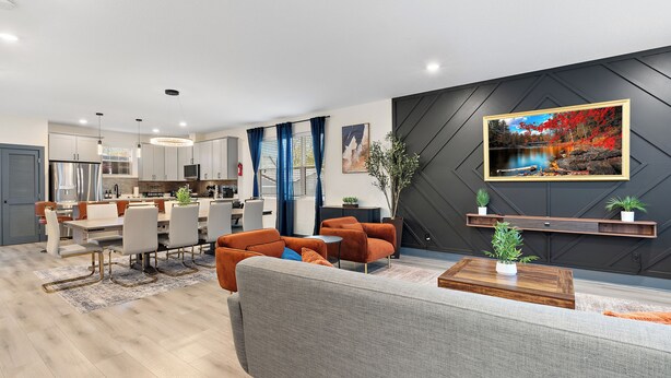 Una sala moderna con un sofá gris, sillones naranja y una mesa de centro de madera.