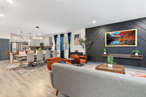 A modern living room with a grey sofa, orange chairs, and a wooden coffee table. - 14guests, gameroom, theatre, sauna in the center of twin cities  (Saint Paul)