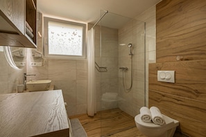 Ein modernes Badezimmer mit einer gläsernen Dusche, einem Holzlappen und einer Toilette mit Handtüchern.