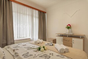 Une chambre dâhĂŽtel avec un lit, une table de chevet, une commode, une fenĂȘtre avec des rideaux et un panneau dâaccueil.