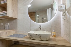 Een badkamer met een marmeren wastafel, een douchecabine van glas, een handdoekrek en een spiegel.