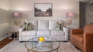 A living room with a sofa, a coffee table, two lamps, and a painting on the wall.
