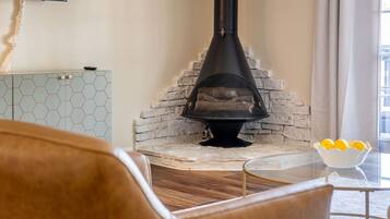 A room with a stone fireplace, a television mounted on the wall, and a table with a bowl of lemons.