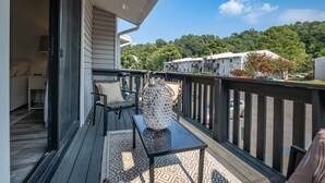 A balcony with a table and chairs, a decorative lantern, and a view of a residential area with trees and buildings.