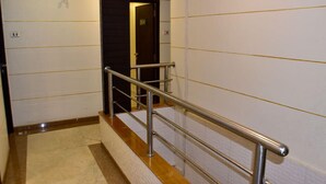 Un escalier avec des rampes en métal, des marches recouvertes d’un tapis beige et des murs blancs ornés de lignes jaunes.