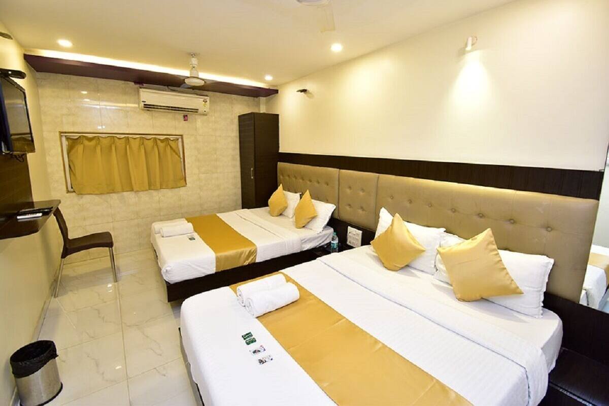 A hotel room with two beds, a desk, a chair, and a trash bin.