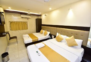 Une chambre d’hôtel avec deux lits, un bureau, une chaise et une poubelle.