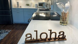 Un piano di lavoro della cucina con top in marmo e un cartello di legno con la scritta "aloha".