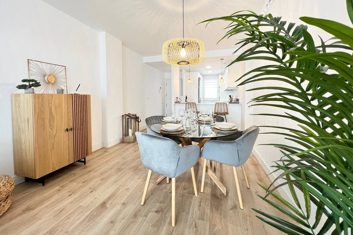 A dining area with a wooden cabinet, a glass table, and two blue chairs.