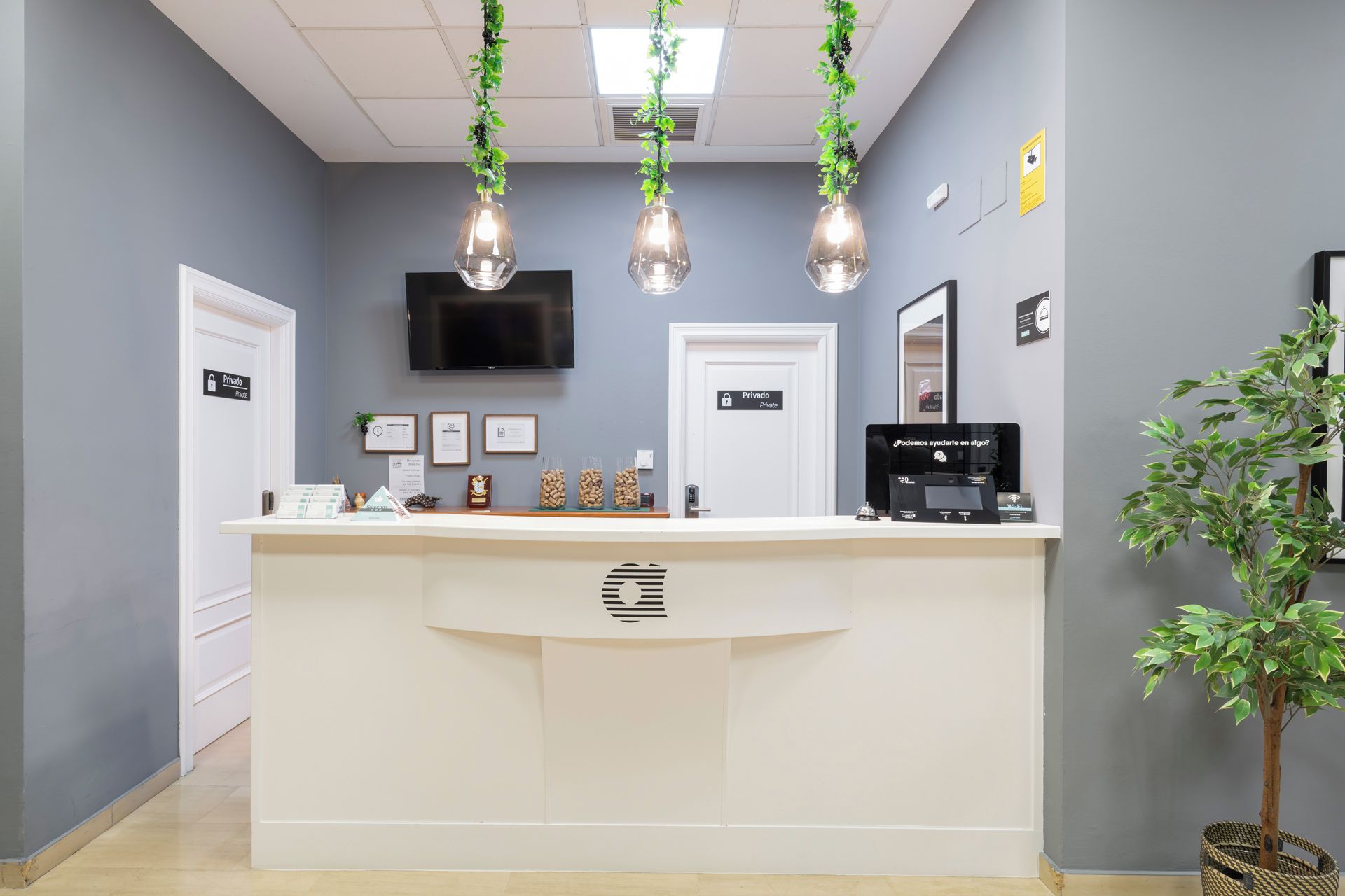 A reception desk with a flat-screen TV above it, a private door, and a self-service kiosk.