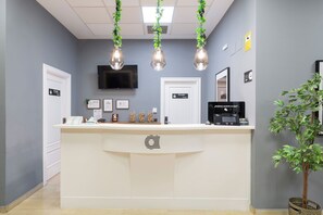 A reception desk with a flat-screen TV above it, a private door, and a self-service kiosk. - Alda Malvasia (Haro)