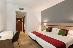 Ein Hotelzimmer mit Bett, Nachttisch, Stuhl und Schreibtisch.