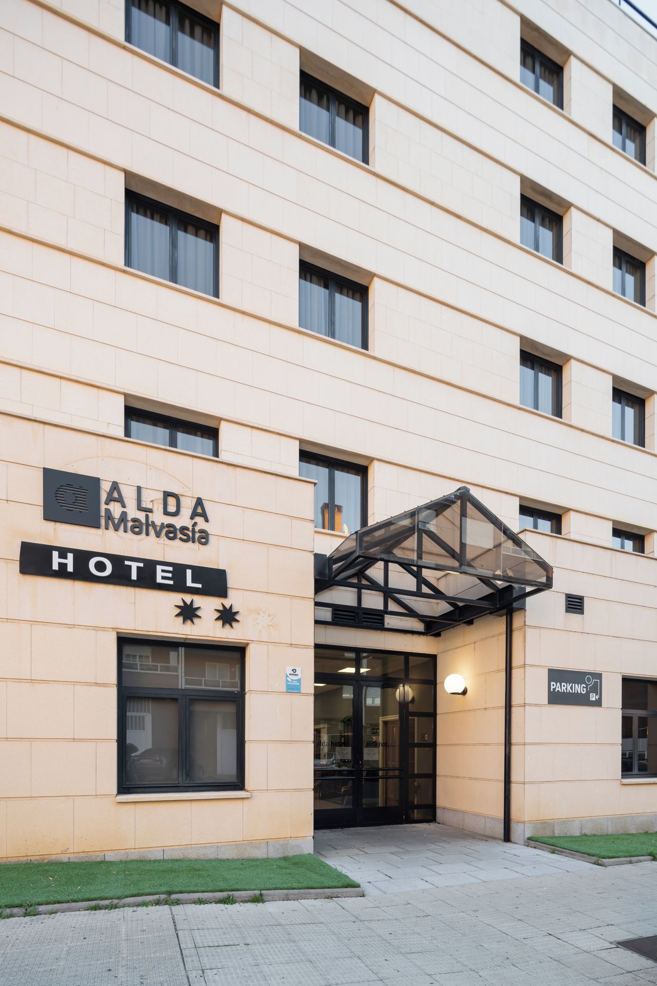 A hotel entrance with a sign reading "ALDA Malvásia HOTEL".