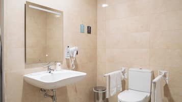 Un baño moderno con lavamanos, espejo, inodoro y toallero.
