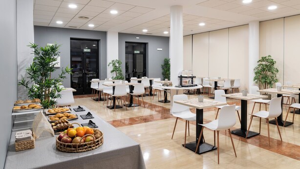 A modern dining area with multiple tables and chairs, a buffet with various food items, and potted plants. - Alda Malvasia (Haro)