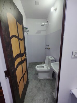 A small, compact bathroom with a toilet, sink, and shower. - Triyuginarayan Maangal Resort  (Ukhimath)