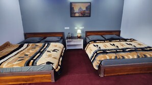 A hotel room with two beds, a nightstand, a lamp, and a painting on the wall. - Triyuginarayan Maangal Resort  (Ukhimath)