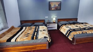 A hotel room with two beds, a nightstand, a lamp, and a painting on the wall. - Triyuginarayan Maangal Resort  (Ukhimath)