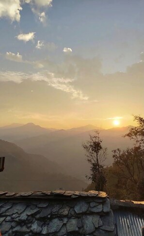 A mountainous landscape with a stone wall in the foreground. - Triyuginarayan Maangal Resort  (Ukhimath)