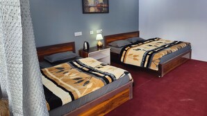 A hotel room with two beds, a nightstand, a lamp, and a painting on the wall. - Triyuginarayan Maangal Resort  (Ukhimath)