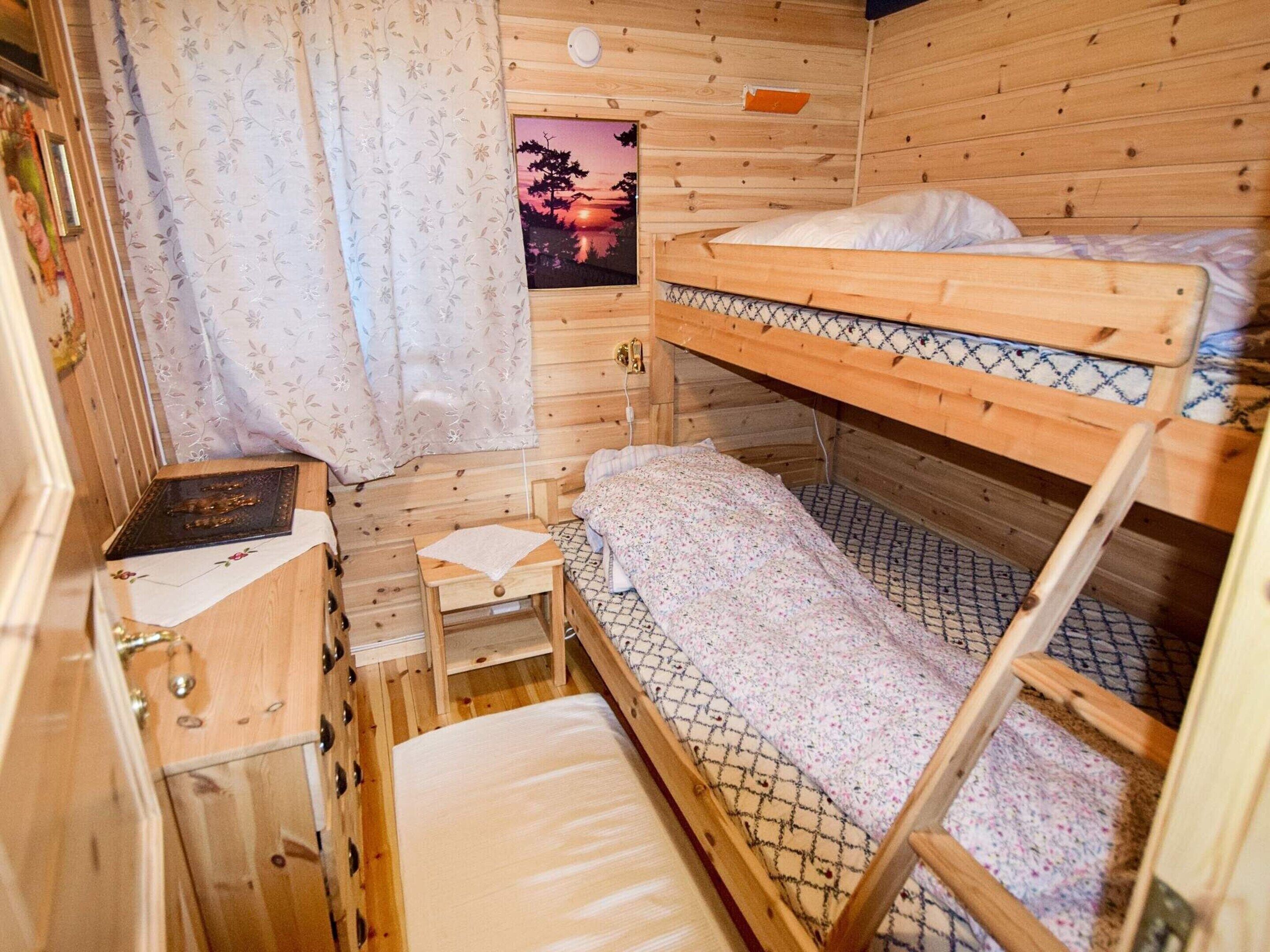 Een houten kamer met stapelbedden, een klein bureau met stoel, en een raam met uitzicht op een zonsondergang.