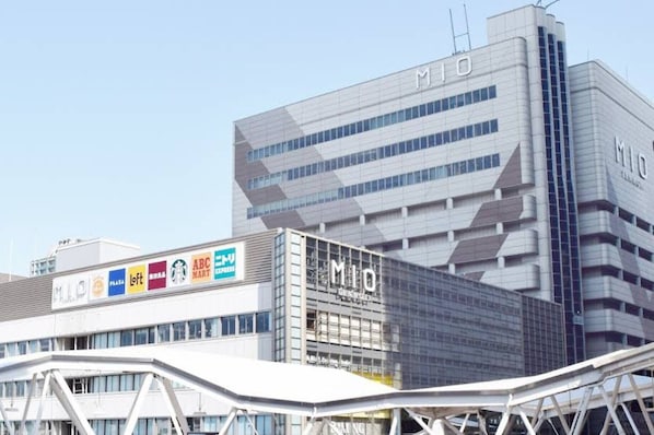 A modern building with the 'MIO' sign, featuring a glass facade and a distinctive geometric design.