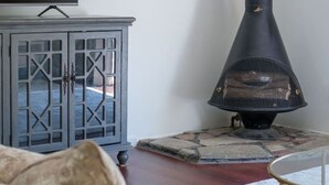 Un salon avec un téléviseur posé sur un meuble, un canapé, une cheminée et un buffet.