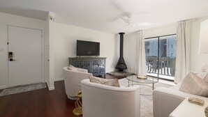 Un salon avec une cheminée, un téléviseur et un balcon offrant une vue agréable.