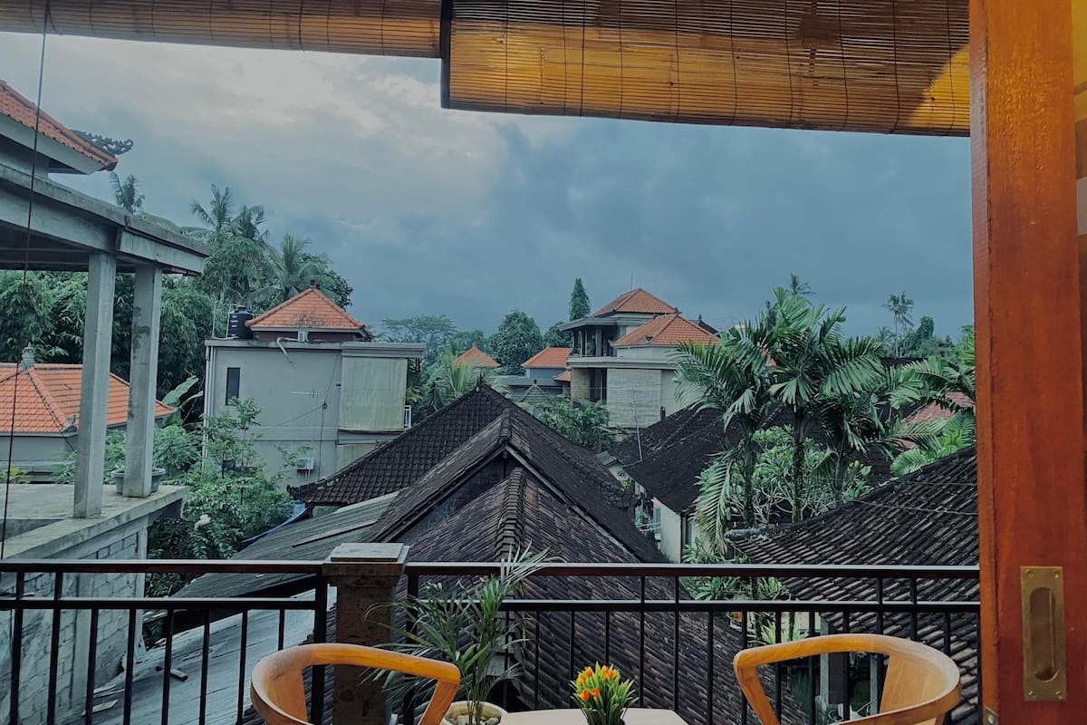 A balcony with a view of traditional houses and lush greenery.
