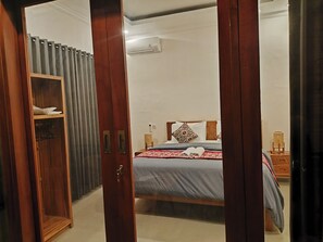 A bedroom with a bed, a wardrobe, and an air conditioning unit.