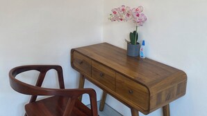 A wooden desk with a drawer, a chair, and a small potted orchid on the desk. - Roberto Suites Ubud View by EPS (Ubud)