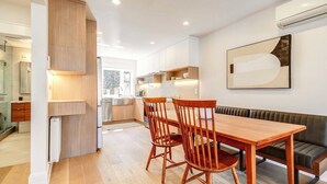 Une cuisine moderne avec des meubles en bois, un coin repas avec une table et des chaises en bois, et un banc intégré.